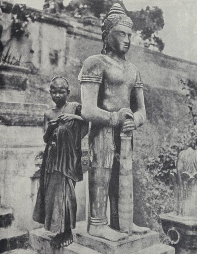 Giovane novizio buddista accanto a una statua del Buddha, Indocina francese da Ewing Galloway