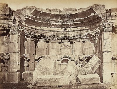Dettaglio delle cosiddette "stanze" nella zona archeologica di Heliopolis o Baalbek, antica città siriana, ora Libano. Un uomo posa, seduto sulle rovine da Félix Bonfils
