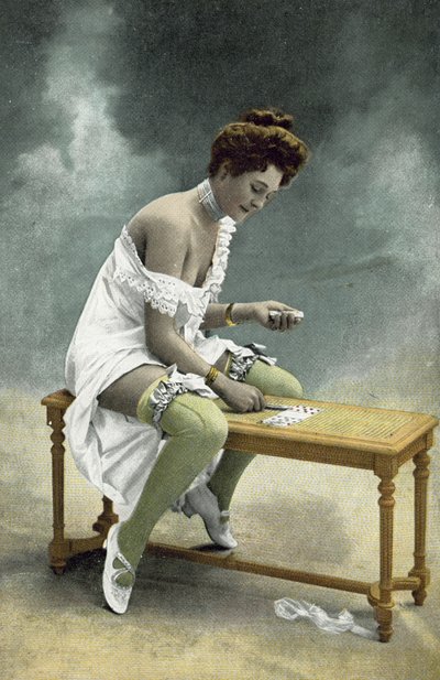 Ragazza con calze e seno esposti che gioca a pazienza su uno sgabello di legno da French Photographer