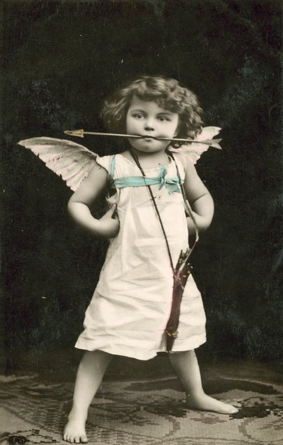 Bambino piccolo, vestito da Cupido, con una freccia in bocca da French Photographer