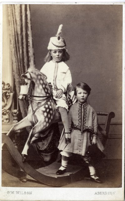Ragazzina con cappello su cavallo a dondolo con un