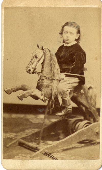 Ragazzino con frusta su cavallo a dondolo da John McCaffrey