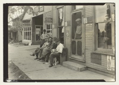 Uomini con cane seduti su una panchina di fronte al negozio generale da Lewis Wickes Hine