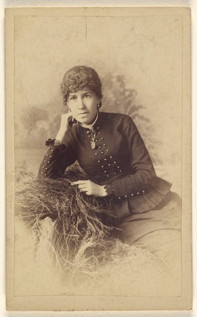 [Donna non identificata seduta con la mano sulla guancia, in posa su un mucchio di fieno]. da Miller and Company