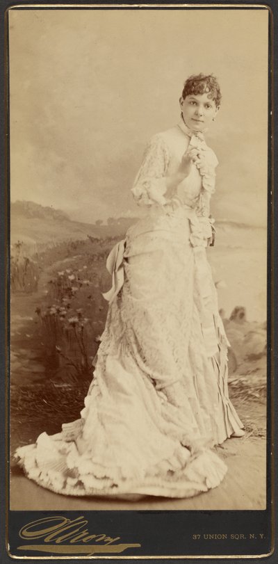 [Donna non identificata che indossa un lungo ed elegante abito bianco, in piedi] da Napoleon Sarony