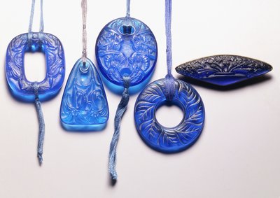 Quattro pendenti in vetro turchese e una spilla in vetro montata in metallo dorato da Rene Jules Lalique