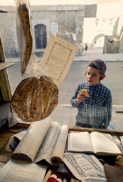 Ragazzo ebreo conservatore che mangia una torta guarda in una libreria religiosa da Ted Spiegel