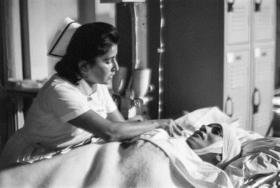 Infermiera aiuta un paziente su una barella dopo un intervento chirurgico sulla nave ospedale SS Hope da Ted Spiegel