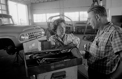 Autista di camion Mildred Cooper chiacchiera con un meccanico in un garage da Ted Spiegel