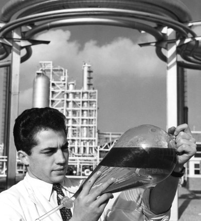 Un lavoratore di laboratorio tiene un imbuto separatore di olio, raffineria di Dunkerque, Francia, anni 