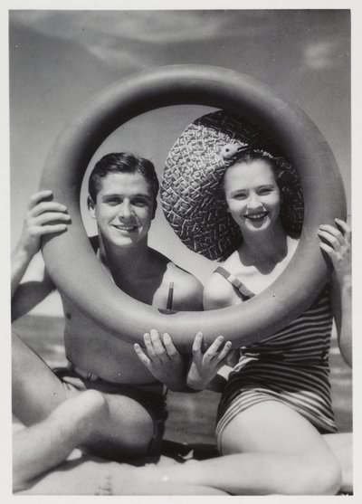 Uomo e donna che guardano attraverso un anello di gomma sulla spiaggia, c 1935 da Unbekannt