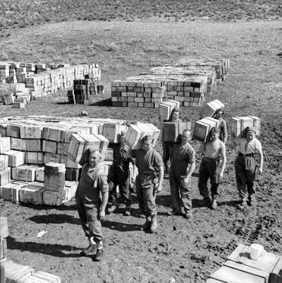 Un deposito di razioni composte e uomini che trasportano altre provviste, marzo 1943 da Unbekannt