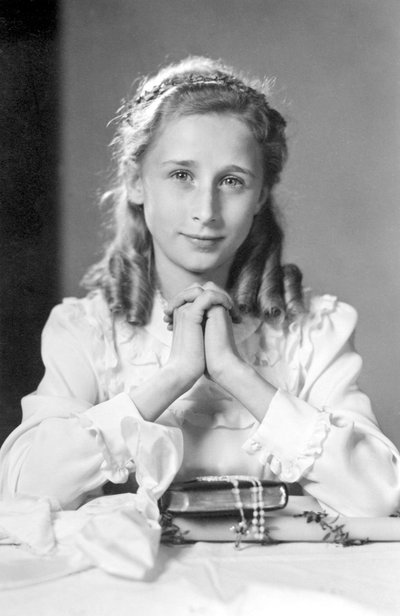 Ragazza cristiana con mani giunte in posizione di preghiera con bibbia, rosario e candela (foto di comunione). Fotografia intorno al 1932 da Unbekannt