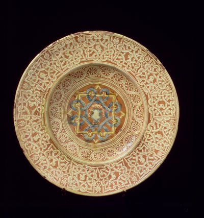 Piatto di maiolica decorato con un elaborato disegno a nodo ripetitivo che incornicia teste di profilo sul bordo e uno scudo nella placca centrale, italiano, fatto in Toscana da Unknown