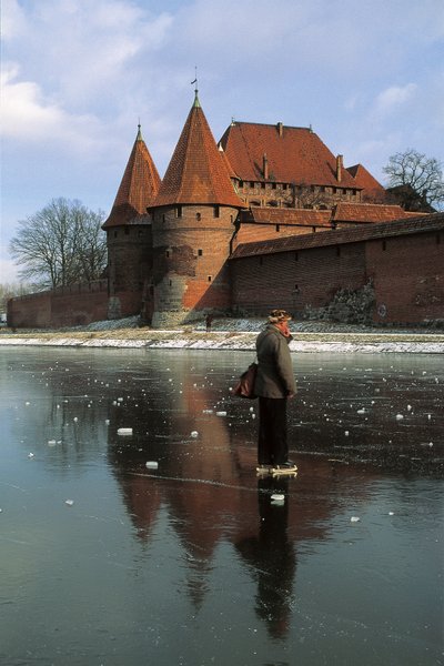 Profilo laterale di un uomo che si trova su un fiume ghiacciato davanti a un castello, fiume Nogat, castello di Malbork, Malbork, provincia di Pomorskie, Polonia da Benjamin Baud