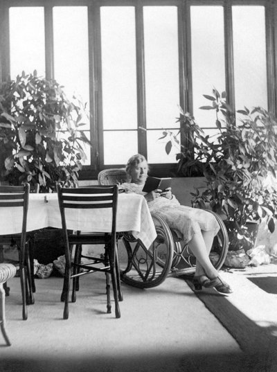 Donna seduta su una sedia a dondolo, che legge un libro. 1915 ca. Germania Foto storica, donna che legge, ca. 1915 da Unbekannter Künstler
