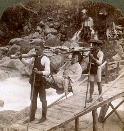 Donna giapponese in una sedia da montagna yamakago attraversa il torrente Daiya vicino a Nikko, Giappone da Underwood and Underwood