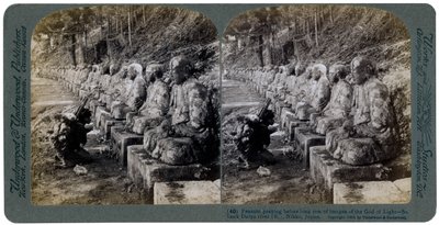Contadino che prega davanti a una fila di statue del Dio della Luce, fiume Daiya, Nikko, Giappone da Underwood and Underwood