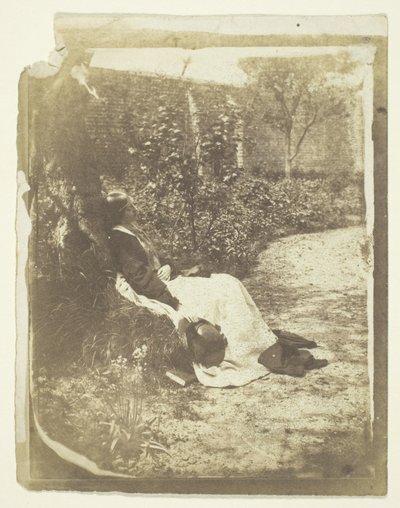 Mrs. Craik sdraiata in giardino con cappello e libro da Unknown