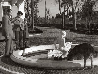 Gino Bartali con due bambini e un cane vicino a una fontana da Unknown photographer