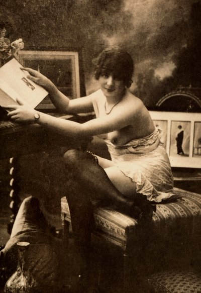 Ritratto di una giovane donna in abbigliamento intimo, seduta a un tavolo con un libro da Unknown photographer