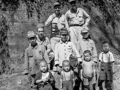 Soldati americani con una famiglia giapponese posano insieme dopo la resa giapponese da Volkmar Wentzel