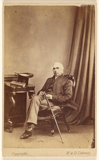 [Uomo non identificato dai capelli bianchi seduto, con bastone, cappello a cilindro e libro sul tavolo a sinistra]. da W. and D. Downey