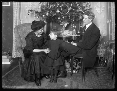 Dan Seymour e famiglia in posa informale, seduti sotto un albero di Natale, Natale 1912 da William Davis Hassler