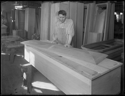 Lavoratore che adatta un pezzo di coperchio di una bara, Oneida, New York, 3 aprile 1916 da William Davis Hassler