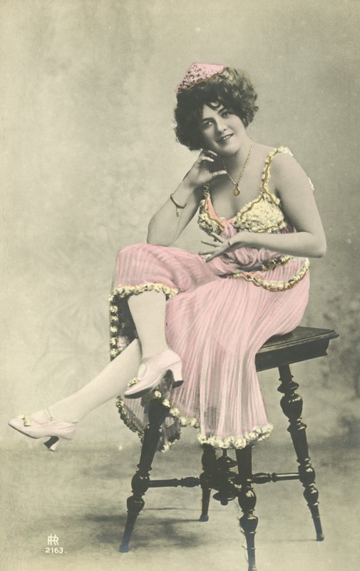 Attrice con bel sorriso in abito rosa seduta su uno sgabello da French Photographer