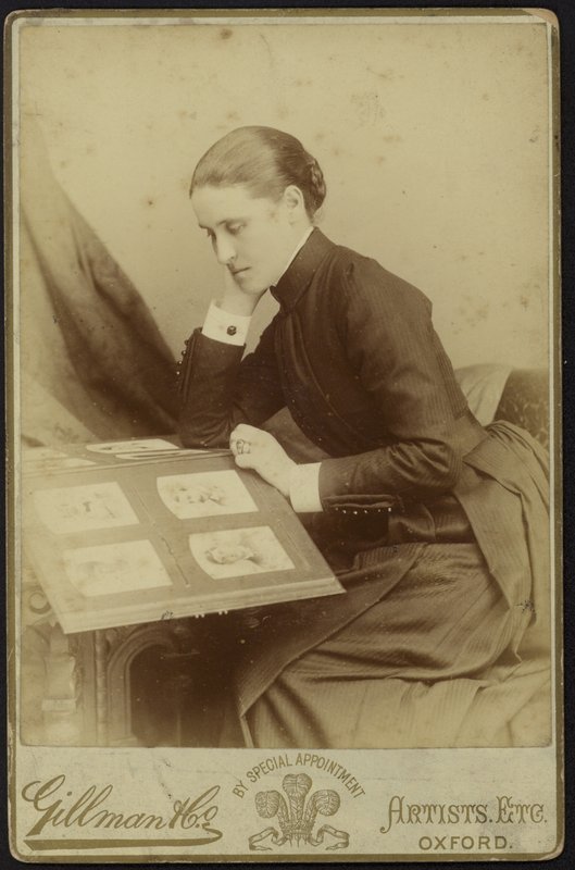 Figura di una donna seduta che ispeziona un album fotografico da English Photographer
