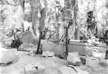 Scavatori al lavoro in una cava di marmo nelle Alpi Apuane, Toscana. In primo piano ci sono blocchi di marmo già squadrati