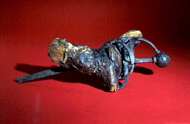 Spada nella radice di un albero (ferro e legno)