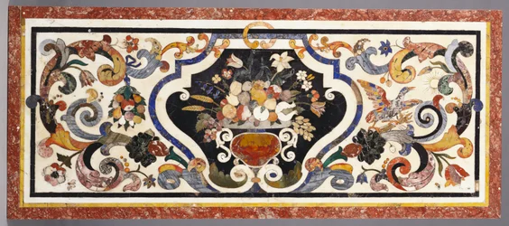 Tavolo in pietra dura fiorentina centrato da una ciotola di frutta e fiori