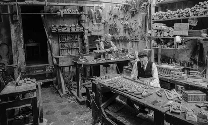 Artigiani a un banco di lavoro in un laboratorio che fabbricano piccoli oggetti di legno