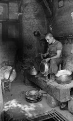 Fabbro italiano che martella su una lamiera per fare un vaso o una pentola, Italia