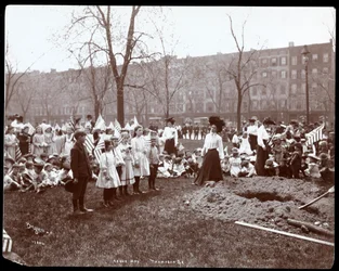 Adulti e bambini con bandiere intorno a una buca appena scavata per la piantagione di un albero nel Tompkins Square Park, New York