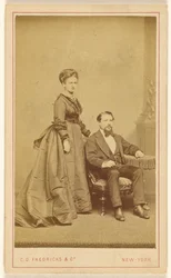 [Coppia non identificata: donna in piedi, uomo con barba Vandyke seduto].