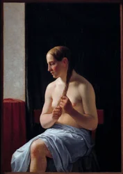Modello nudo seduto. Ritratto di una donna che si intreccia i capelli