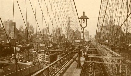Lower Manhattan visto attraverso la rete di cavi sul ponte sospeso di Brooklyn, c1930