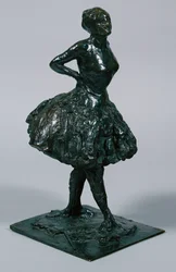 Ballerina in abito casual, con le mani sui fianchi, la gamba destra in avanti, fusa c.1919-21