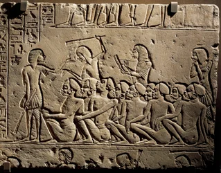 Un gruppo di prigionieri neri circondati da guardie armate di clave mentre uno scriba redige un rapporto, rilievo dalla tomba di Horemheb a Saqqara