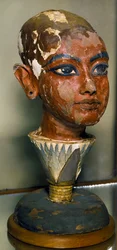 Antichità egizia: ritratto del giovane faraone Tutankhamon sostenuto da una foglia di loto. Scultura in legno dipinto. Dal tesoro di Tutankhamon. Museo Egizio, Il Cairo