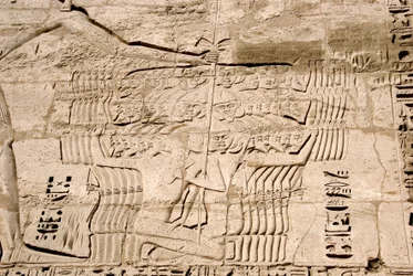 Antichità egizia: dettaglio dei rilievi del primo pilone che rappresentano la cattura di combattenti appartenenti ai popoli del mare, nemici di Ramses III. Tempio funerario di Ramses III (1187-1156 a.C.). Luxor, Medinet Habou, Egitto