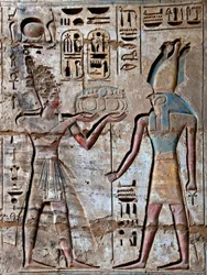 Antichità egizia: primo cortile, dettaglio di rilievi dipinti che raffigurano il faraone che porta offerte alla divinità Horus (Tempio funerario di Ramses III, Luxor, Medinet Habu, Egitto)