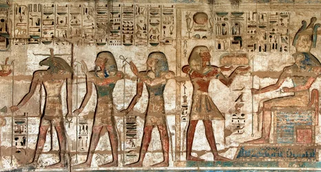 Antichità egizia: primo cortile, dettaglio di rilievi dipinti che raffigurano il faraone che porta offerte alle divinità Horus e Khnoum. Tempio funerario di Ramses III (1187-1156 a.C.). Luxor, Medinet Habou, Egitto