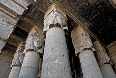 Antichità egizia: vista parziale della sala ipostila con colonne decorate con la rappresentazione della dea Hathor. Tempio di Hathor, Denderah, Egitto