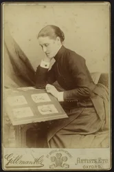 Figura di una donna seduta che ispeziona un album fotografico