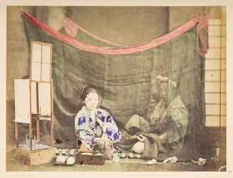Coppia giapponese nel tempo libero, Tableau in studio di una giovane donna giapponese, seduta con attrezzi per il tè intorno a lei, che porge una pipa a una figura maschile che siede dietro di lei, protetta da una zanzariera di lino, Fotografo: Sconosciut