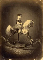 Bambina seduta su un cavallo a dondolo maculato
